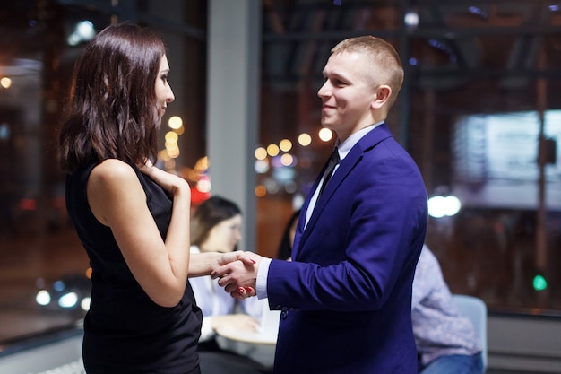 Group of young office managers celebrate the successful completion of the transaction Man shakes hands with a business woman Teamwork deadlines urgent order