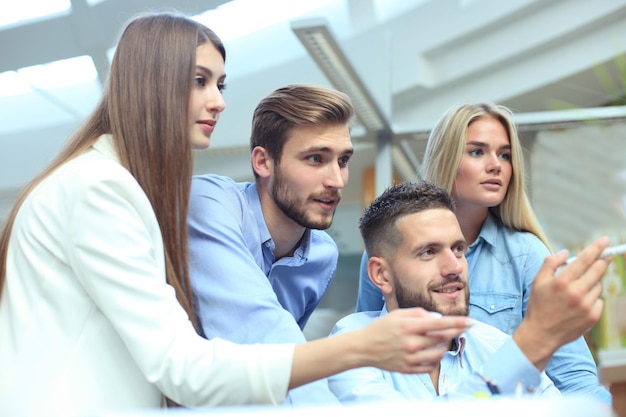 Photo group of young people in casual wear sitting at the office desk and discussing something while looking at pc together.