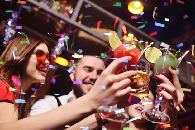 Group of young people celebrate a birthday or christmas on a nightclub and salute their confetti