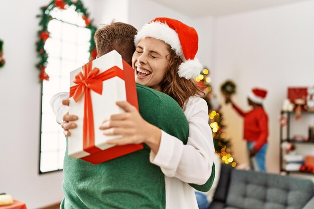 크리스마스 회의에 젊은 사람들의 그룹입니다. 선물을 들고 집에서 포옹하는 커플.