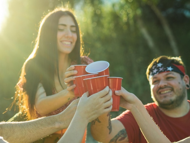 Foto gruppo di giovani che tintinnano tazze rosse di plastica a una festa