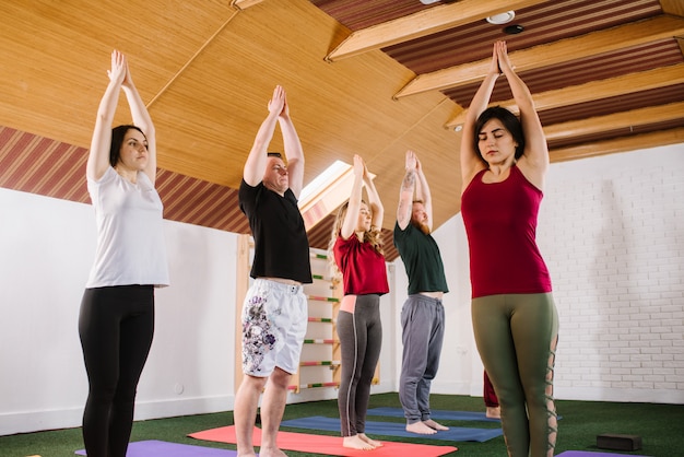 A group of a young people doing joga exercises indoors at the gym