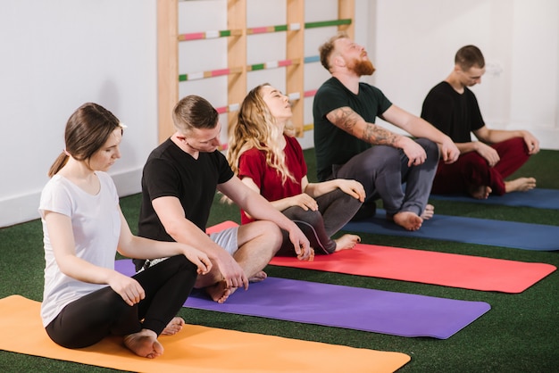 A group of a young people doing joga exercises indoors at the gym