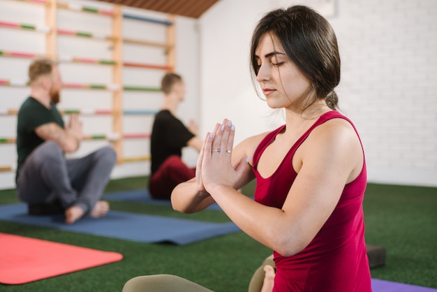 A group of a young people doing joga exercises indoors at the gym