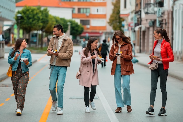 A group of young people dressed in modern clothes talk while walking around the city and eating sweets Selective focus