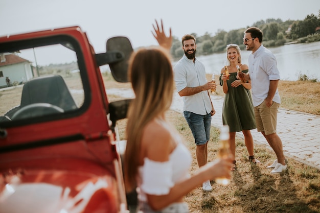 Group of young people drinking and having fun by car outdoor