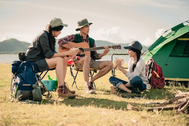 Group of young people enjoy in music of drums and guitar on\
camping trip.