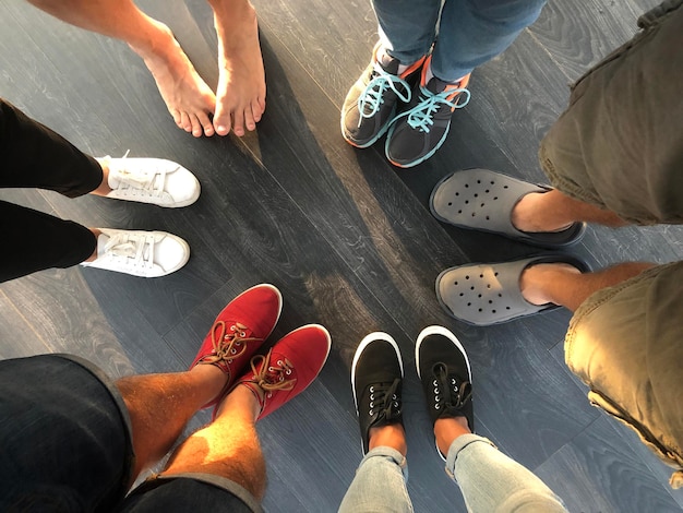 Group of young people feet stand in a circle Five people in shoes and one barefoot