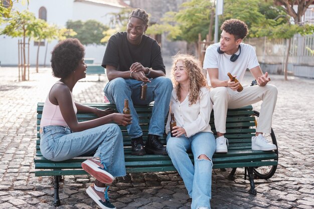 Группа молодых людей, пьющих пиво вместе на открытом воздухе в городском парке Концепция веселой дружбы