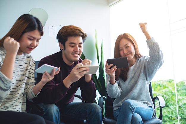 A group of young people having fun and celebrating while watching and playing games on mobile phone together