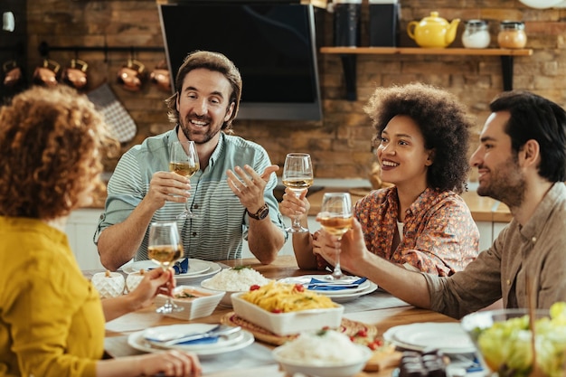 Gruppo di giovani che si divertono e brindano con il vino durante l'ora di pranzo a casa