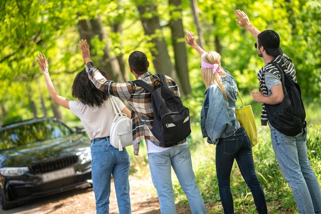 Photo group of young people hitchiking on the road