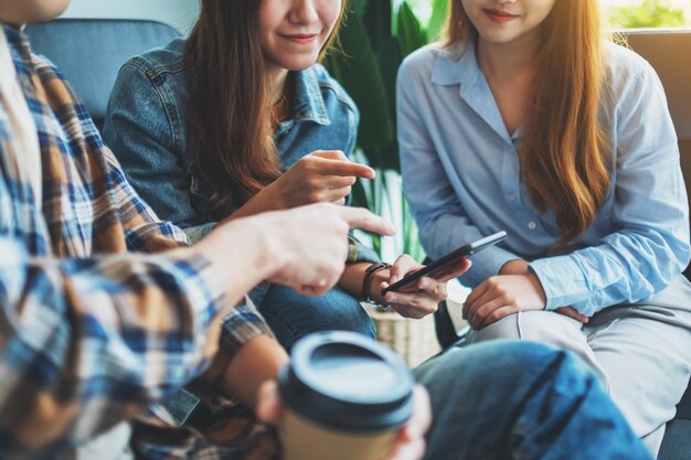 一緒にぶら下がっている間同じ携帯電話を見ている若者のグループ