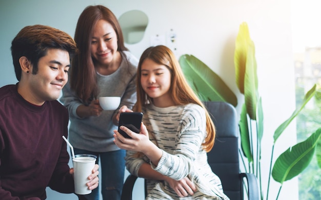 A group of young people looking at the same mobile phone while hanging together