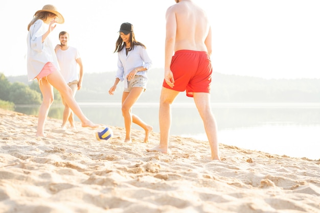 ビーチでボールで遊ぶ若者のグループ。砂浜で夏休みを楽しんでいる若い友達。