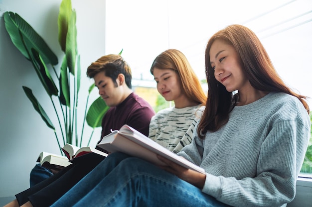 Gruppo di giovani seduti e divertito a leggere libri insieme