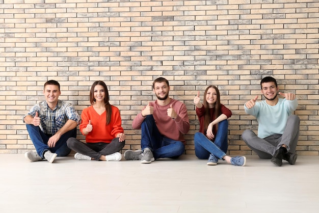 Foto gruppo di giovani seduti insieme sul pavimento al chiuso concetto di unità