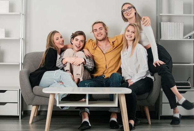 Group of young people sitting on sofa and talking at home students party