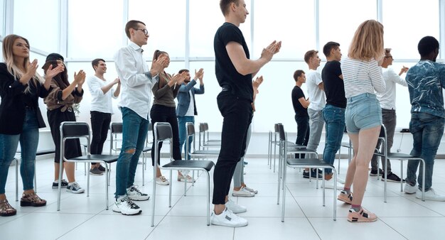 Group of young people standing applauding in the conference\
room