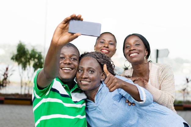 group of young people taking a picture with a mobile phone to mark their reunion
