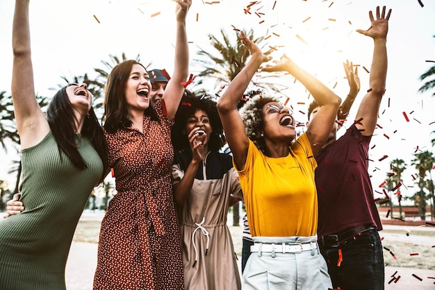 Photo group of young people throwing confetti in the air making festival party