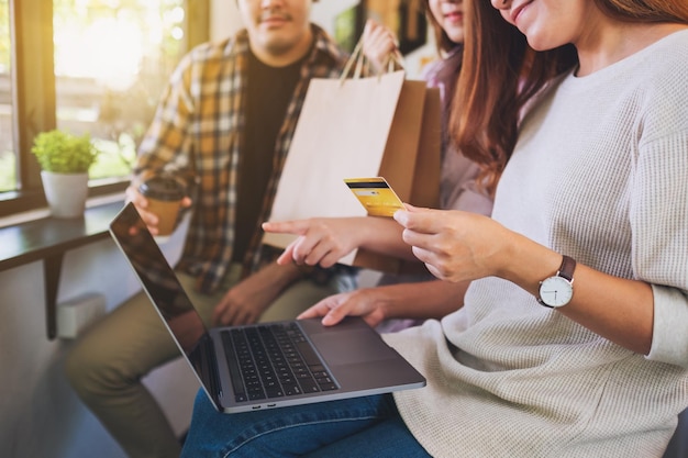 Group of young people using laptop and credit card for shopping online together