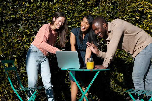 Group of young people using laptop together outdoors