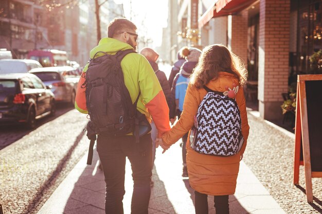 A group of young people walk the streets of Berlin in the winter. Some couples hold hands. Shot in backlight with a bright sun