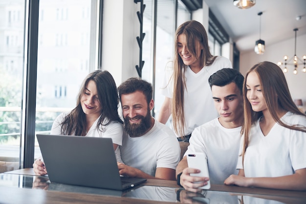 Un gruppo di giovani con gadget e laptop organizza un brainstorming e comunica tra loro. il concetto di sviluppare una giovane impresa.