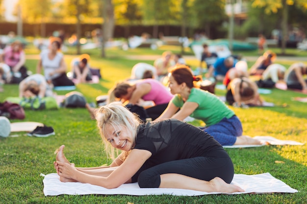 Un gruppo di giovani fa yoga nel parco al tramonto.
