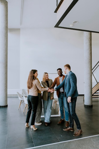 Group of young positive businesspeople standing together in the office