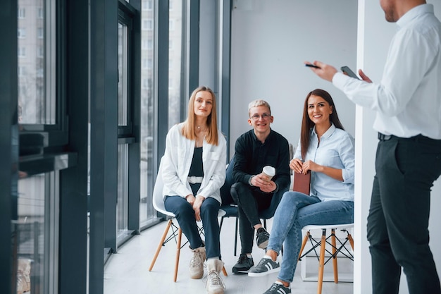 Group of young positive team have work and communicating together indoors in office near windows