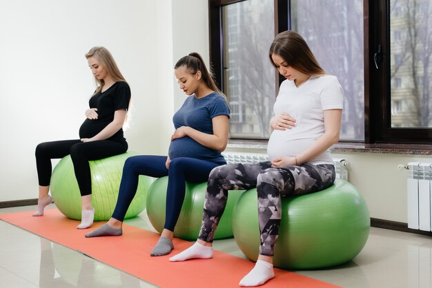 젊은 임신 어머니 그룹은 헬스 클럽에서 필라테스와 공 스포츠에 종사하고 있습니다. 충만한