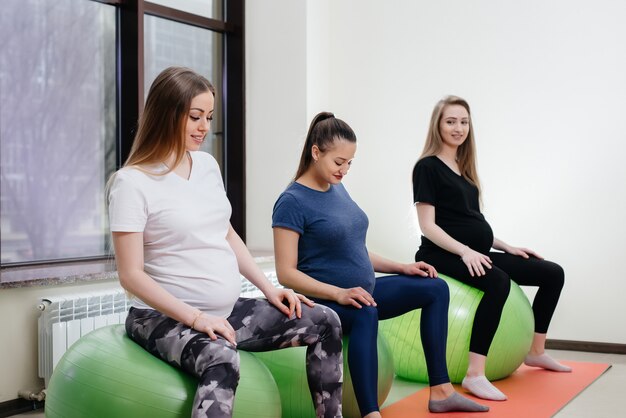 A group of young pregnant mothers are engaged in Pilates and ball sports at a fitness club. Pregnant.