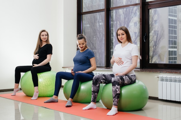 A group of young pregnant mothers are engaged in Pilates and ball sports at a fitness club. Pregnant