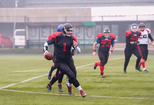 Group of young professional american football players in action\
during training match on the stadium field