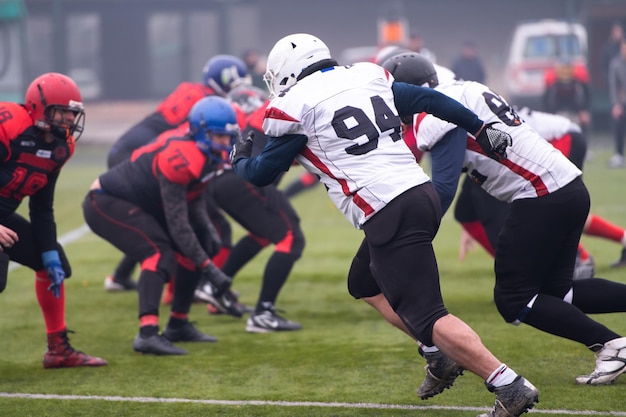 Group of young professional american football players in action\
during training match on the stadium field