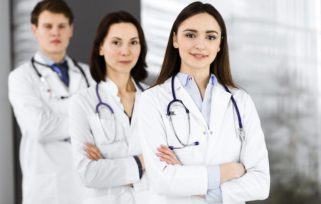 Group of young professional doctors is standing as a team with\
arms crossed in a hospital office and is ready to help patients.\
medical help, insurance in health care, best disease treatment and\
medic