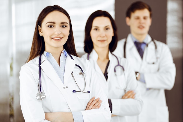 Photo group of young professional doctors is standing as a team with arms crossed in a hospital office and is ready to help patients