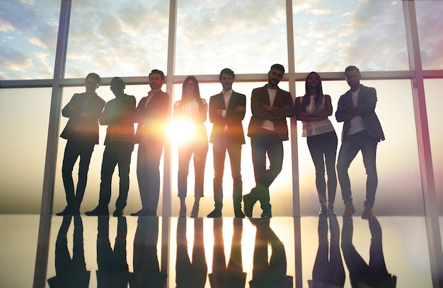 Group of young professionals standing in an office with a large window