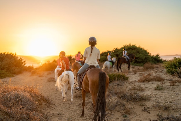 Gruppo di giovani cavalieri a cavallo diretti verso la spiaggia