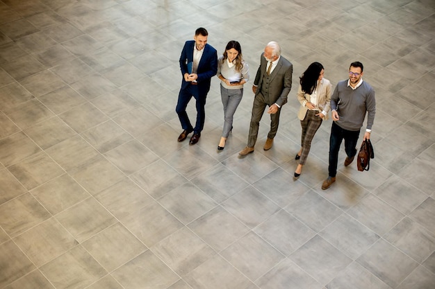 A group of young and senior business people are walking in office hallway captured in aerial view