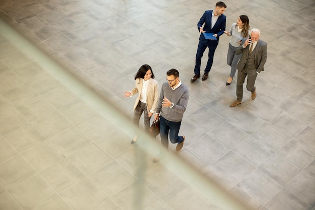 A group of young and senior business people are walking in office hallway captured in aerial view