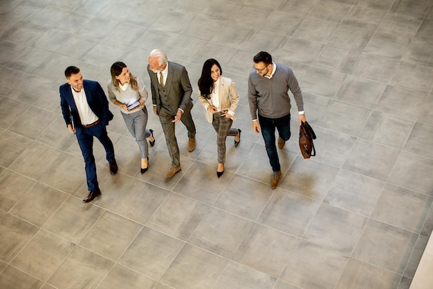 A group of young and senior business people are walking in an office hallway