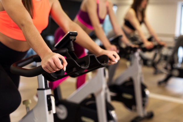 Group of young slim women workout on exercise bike in gym. 