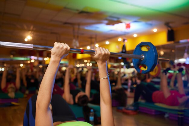 Group of young sport people training with barbell at a gym for better fitness