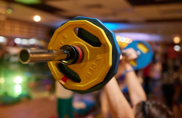 Photo group of young sport people training with barbell at a gym for better fitness