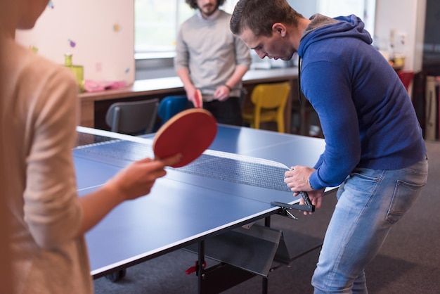 group of young startup business people playing ping pong tennis at modern creative office