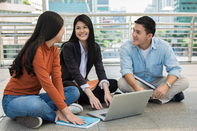 Group of young student people study and reading together in university hall during break with books and laptop computer