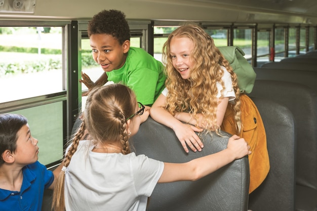 Group of young students attending primary school on a yellow school bus - Elementary school kids ha1ving fun